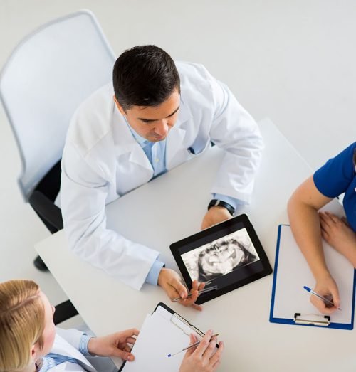 medicine, healthcare and oral surgery concept - group of doctors or surgeons discussing jaw x-ray on tablet pc computer screen at hospital or face and jaw surgery center